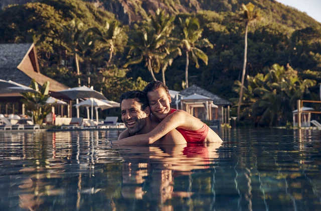 Casal na piscina do Club Med Seychelles, cercada por vegetação tropical