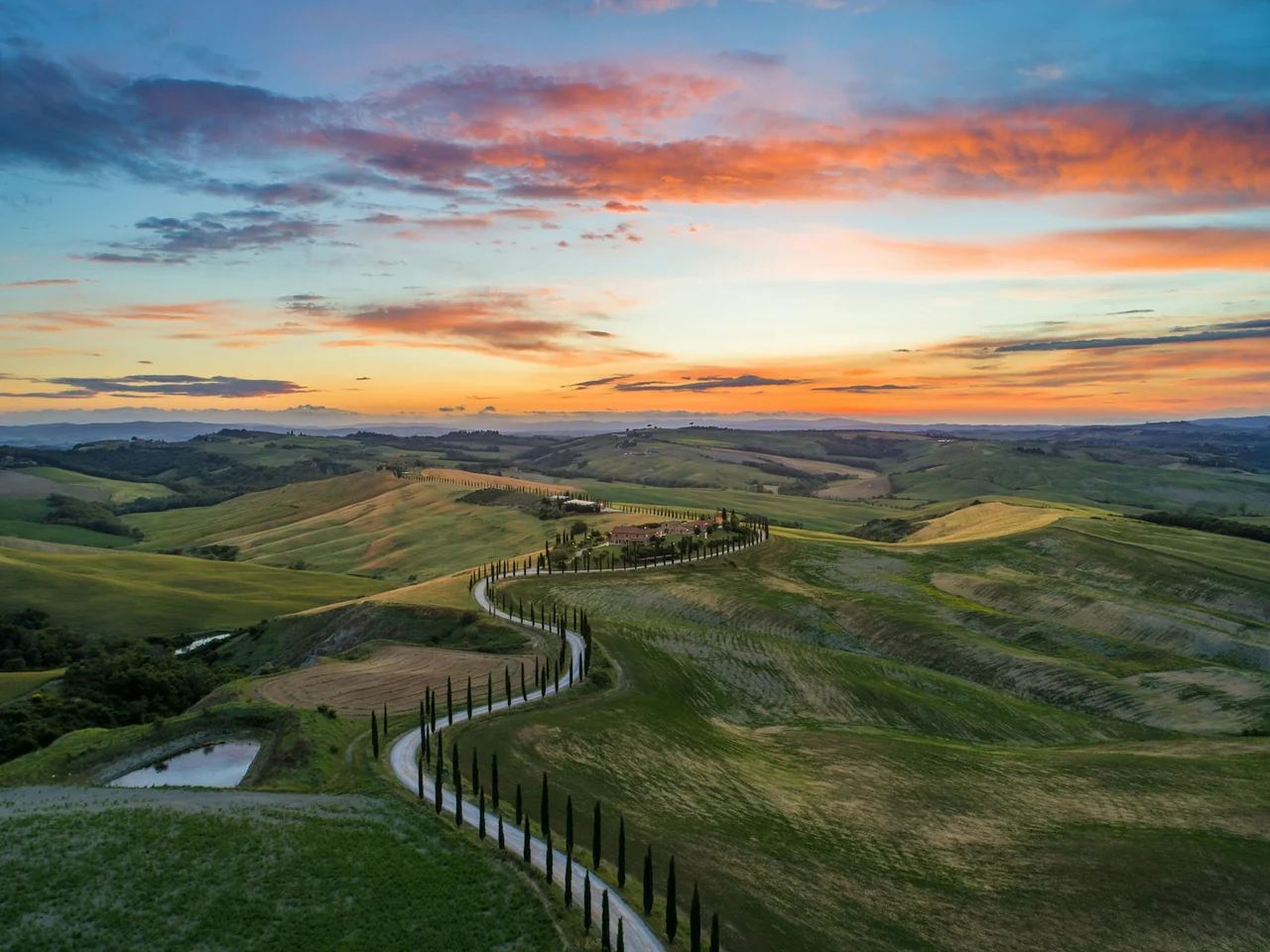 Estrada entre colinas e ciprestes da Toscana, Itália, ao pôr do sol